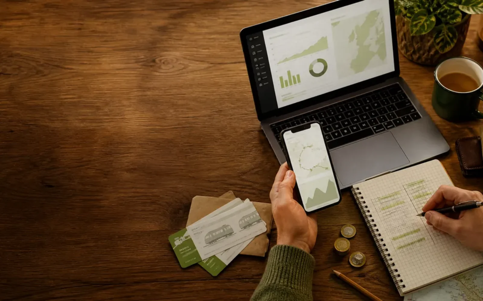 A traveler comparing routes and costs with a laptop, phone and paper notebook