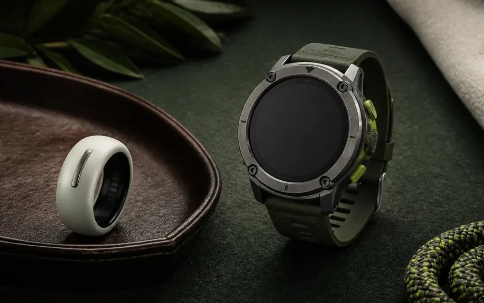 A screenless health ring displayed beside a rugged sports watch
